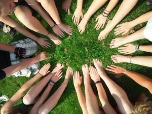 photo de jeunes assis sur le gazon avec leurs pieds et leurs mains formant un cercle